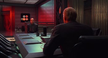 Movie still from “Total Recall” (1990), directed by Paul Verhoeven – Two men sitting at a table in front of each other; Medium shot, Over the shoulder angle