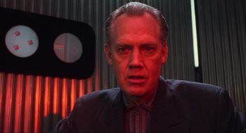 Movie still from “Total Recall” (1990), directed by Paul Verhoeven – A person wearing a suit and tie; Close Up shot, Low angle