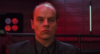 Movie still from “Total Recall” (1990), directed by Paul Verhoeven – A man in a black shirt and black jacket; Close Up shot, Low angle