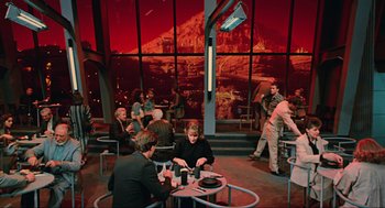 Movie still from “Total Recall” (1990), directed by Paul Verhoeven – A group of people sitting at a table in a restaurant; Wide shot, High angle