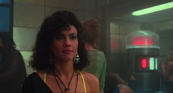 Movie still from “Total Recall” (1990), directed by Paul Verhoeven – A woman in a black and yellow dress and some other women; Close Up shot, Over the shoulder angle