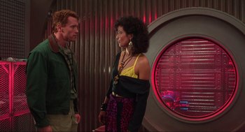 Movie still from “Total Recall” (1990), directed by Paul Verhoeven – A man and a woman standing next to each other in front of a wall; Medium shot, Over the shoulder angle