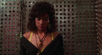 Movie still from “Total Recall” (1990), directed by Paul Verhoeven – A woman wearing a black and yellow dress and a necklace; Close Up shot, Low angle