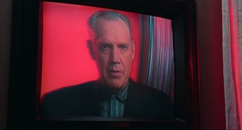 Movie still from “Total Recall” (1990), directed by Paul Verhoeven – An older man in a suit and tie on a television screen; Close Up shot, Low angle