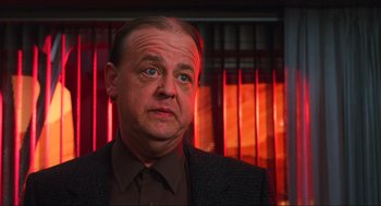 Movie still from “Total Recall” (1990), directed by Paul Verhoeven – A person wearing a suit and tie; Close Up shot, Low angle