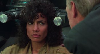 Movie still from “Total Recall” (1990), directed by Paul Verhoeven – A woman with curly black hair is being examined by a man; Close Up shot, Over the shoulder angle
