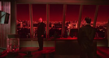 Movie still from “Total Recall” (1990), directed by Paul Verhoeven – A man standing in front of a large window with a view of a city; Wide shot, Over the shoulder angle