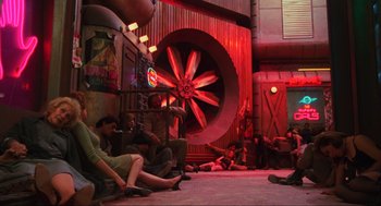 Movie still from “Total Recall” (1990), directed by Paul Verhoeven – A group of people sitting on the ground in a room; Wide shot, High angle