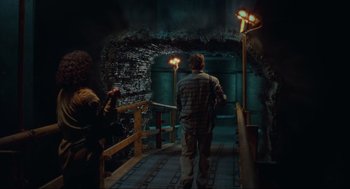 Movie still from “Total Recall” (1990), directed by Paul Verhoeven – A man walking down a stair way in a building; Wide shot, Low angle