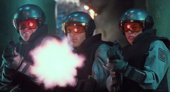 Movie still from “Total Recall” (1990), directed by Paul Verhoeven – A group of men wearing helmets and holding guns in front of a cloud of smoke; Medium shot, Low angle