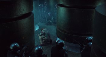 Movie still from “Total Recall” (1990), directed by Paul Verhoeven – A man kneeling down next to a group of soldiers; Wide shot, High angle