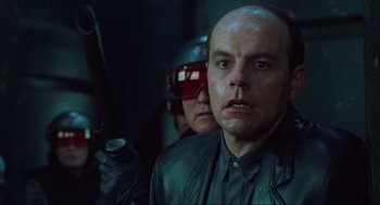 Movie still from “Total Recall” (1990), directed by Paul Verhoeven – A man in a leather jacket holding a gun in his hand; Close Up shot, Low angle