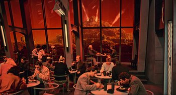 Movie still from “Total Recall” (1990), directed by Paul Verhoeven – A group of people sitting at tables in front of a window; Wide shot, High angle