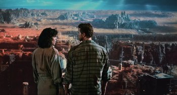 Movie still from “Total Recall” (1990), directed by Paul Verhoeven – A man and a woman standing in front of a painting; Wide shot, High angle