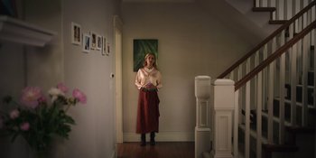 Movie still from “Totally Killer” (2023), directed by Nahnatchka Khan – A woman standing in front of a painting in a room; Wide shot, Low angle