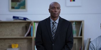 Movie still from “Totally Killer” (2023), directed by Nahnatchka Khan – A man wearing a suit and tie standing in a room; Medium shot, Over the shoulder angle