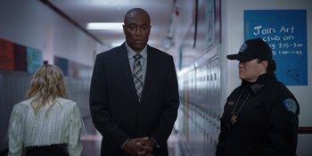 Movie still from “Totally Killer” (2023), directed by Nahnatchka Khan – A man in a suit and tie standing in a hallway; Medium shot, Low angle