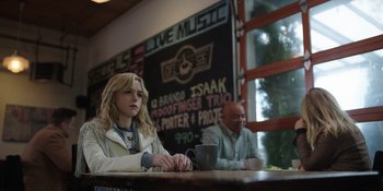 Movie still from “Totally Killer” (2023), directed by Nahnatchka Khan – A woman sitting at a table in front of a man drinking coffee; Medium shot, Low angle