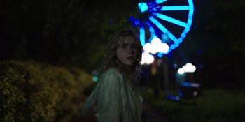 Movie still from “Totally Killer” (2023), directed by Nahnatchka Khan – A woman standing in front of a ferris wheel at night; Medium shot, Over the shoulder angle
