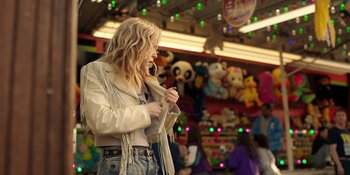 Movie still from “Totally Killer” (2023), directed by Nahnatchka Khan – A woman standing in front of a carnival ride; Medium shot, Over the shoulder angle