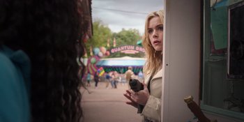Movie still from “Totally Killer” (2023), directed by Nahnatchka Khan – A woman standing in front of an entrance to an amusement park; Medium shot, Over the shoulder angle
