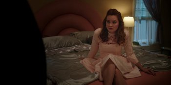 Movie still from “Totally Killer” (2023), directed by Nahnatchka Khan – A woman sitting on the edge of a bed in front of a lamp; Medium shot, High angle
