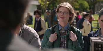 Movie still from “Totally Killer” (2023), directed by Nahnatchka Khan – A young man in a green jacket is holding a backpack; Close Up shot, Over the shoulder angle