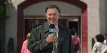 Movie still from “Totally Killer” (2023), directed by Nahnatchka Khan – A man in a green jacket is holding a microphone; Medium shot, Low angle