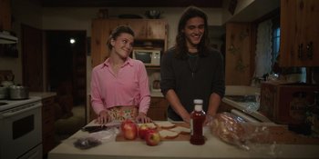 Movie still from “Totally Killer” (2023), directed by Nahnatchka Khan – A man and a woman standing at a table with apples; Medium shot, Low angle