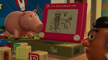 Movie still from “Toy Story 2” (1999), directed by Lee Unkrich – A pig sitting next to a box of blocks and an etch - a - sketch; Extreme Close Up shot, Over the shoulder angle