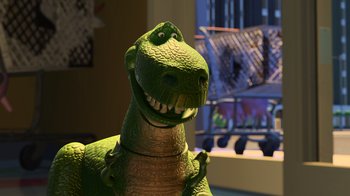 Movie still from “Toy Story 2” (1999), directed by Lee Unkrich – A green toy dinosaur is smiling for the camera; Close Up shot, Low angle