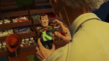 Movie still from “Toy Story 2” (1999), directed by Lee Unkrich – A man holding a toy in his hands; Medium shot, Over the shoulder angle