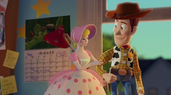 Movie still from “Toy Story 2” (1999), directed by Lee Unkrich – A woman in a pink dress and a man in a cowboy hat are standing next to a cake; Medium shot, Over the shoulder angle