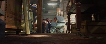 Movie still from “Toy Story 4” (2019), directed by Josh Cooley – A group of men standing around a baby carriage; Wide shot, High angle