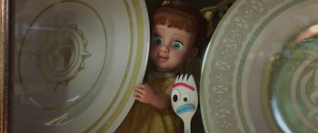 Movie still from “Toy Story 4” (2019), directed by Josh Cooley – A toy doll holding a fork in front of plates and dishes; Close Up shot, Over the shoulder angle