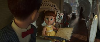 Movie still from “Toy Story 4” (2019), directed by Josh Cooley – A doll is sitting next to a person holding a book; Medium shot, Over the shoulder angle