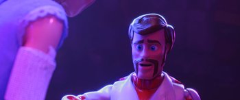 Movie still from “Toy Story 4” (2019), directed by Josh Cooley – A man with a beard and a mustache wearing a white suit; Close Up shot, Over the shoulder angle