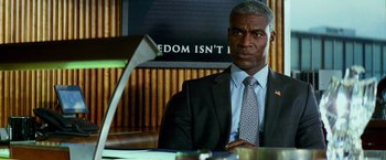 Movie still from “Transformers: Age of Extinction” (2014), directed by Michael Bay – A man sitting at a desk in a suit and tie; Close Up shot, Over the shoulder angle