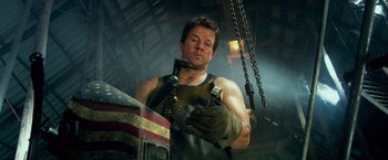 Movie still from “Transformers: Age of Extinction” (2014), directed by Michael Bay – A man in a black shirt and a black glove is working on a piece of metal; Medium shot, Low angle