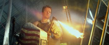 Movie still from “Transformers: Age of Extinction” (2014), directed by Michael Bay – A man holding a hammer in front of an american flag; Medium shot, Low angle