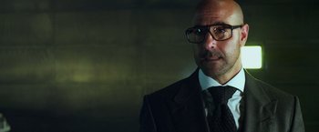 Movie still from “Transformers: Age of Extinction” (2014), directed by Michael Bay – A man in a suit and tie wearing glasses; Close Up shot, Over the shoulder angle