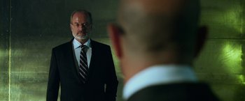 Movie still from “Transformers: Age of Extinction” (2014), directed by Michael Bay – A man in a suit and tie looking at himself in the mirror; Medium shot, Over the shoulder angle