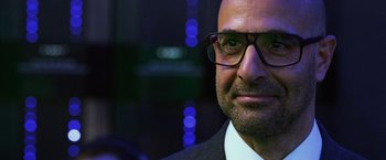 Movie still from “Transformers: Age of Extinction” (2014), directed by Michael Bay – A person wearing glasses and a suit; Close Up shot, Over the shoulder angle