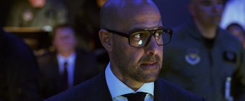 Movie still from “Transformers: Age of Extinction” (2014), directed by Michael Bay – A bald man wearing glasses and a suit; Close Up shot, Over the shoulder angle