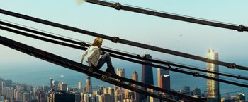 Movie still from “Transformers: Age of Extinction” (2014), directed by Michael Bay – A man sitting on a metal rail on top of a building; Wide shot, High angle