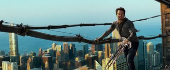 Movie still from “Transformers: Age of Extinction” (2014), directed by Michael Bay – A man is holding onto a rope on a crane; Wide shot, High angle