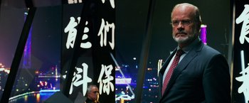 Movie still from “Transformers: Age of Extinction” (2014), directed by Michael Bay – A man in a suit and tie standing in front of a building; Medium shot, Low angle