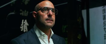 Movie still from “Transformers: Age of Extinction” (2014), directed by Michael Bay – A bald man wearing glasses and wearing a suit; Close Up shot, Low angle