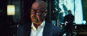 Movie still from “Transformers: Age of Extinction” (2014), directed by Michael Bay – A bald man wearing glasses and a suit; Close Up shot, Low angle