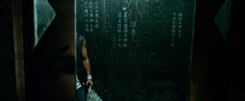 Movie still from “Transformers: Age of Extinction” (2014), directed by Michael Bay – A man standing in front of a green wall with chinese writing on it; Medium shot, Low angle